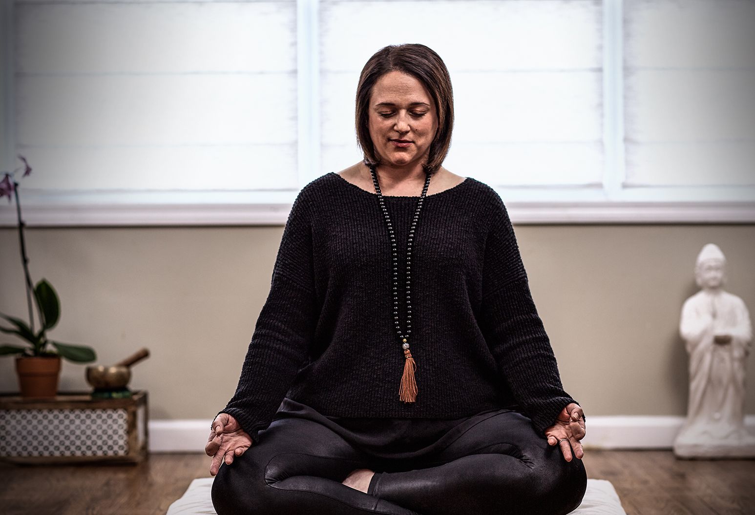 Marissa sitting with legs crossed, meditating.
